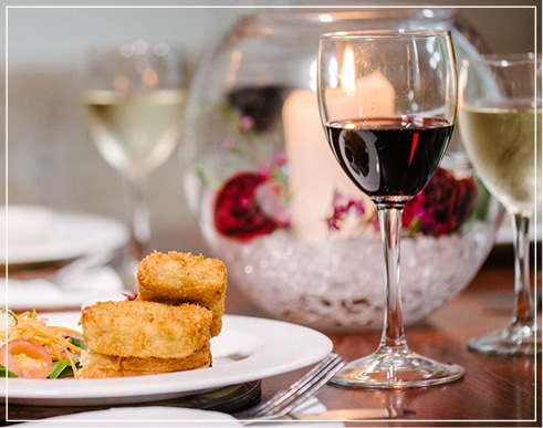 Elegant dining table with gourmet food, wine glasses, and candlelit centerpiece.