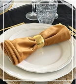 Elegant table setting with white plates, gold cutlery, and a wine glass.