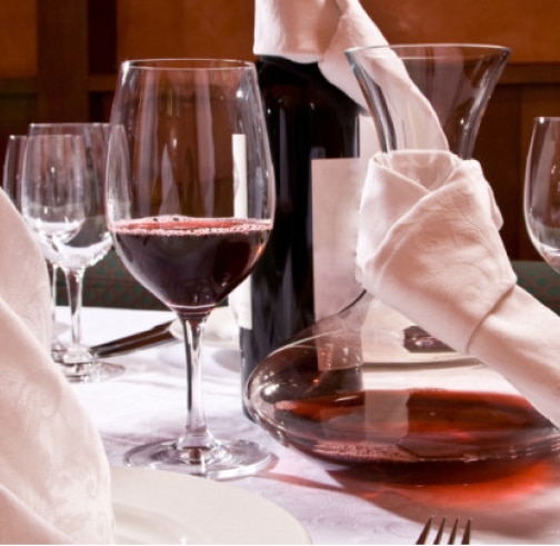 An elegant wine glass filled with red wine next to a bottle
