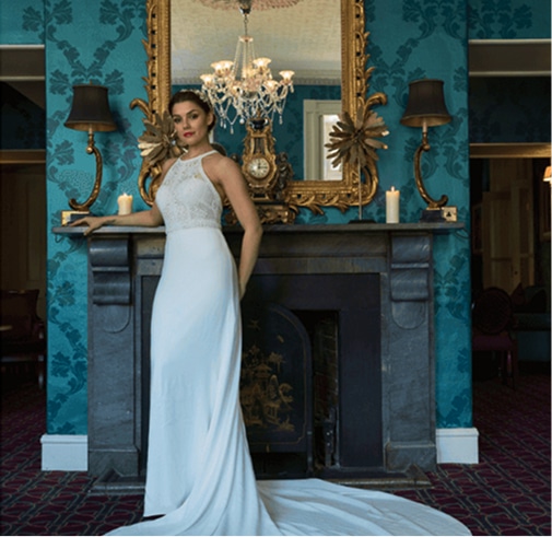 A bride in a wedding dress posing near a cozy fireplace